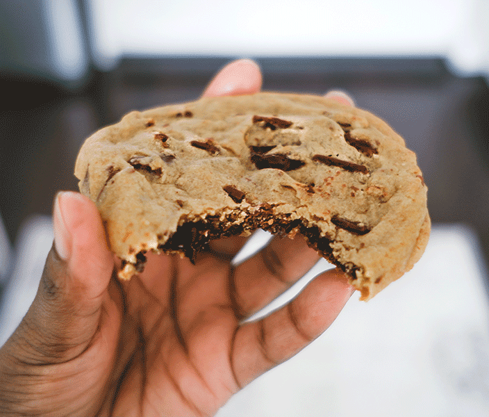A hand holding a chocolate chip cookie